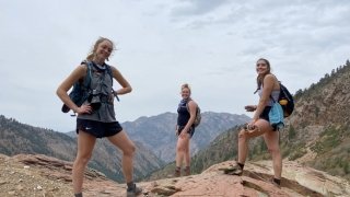 Three Laurentians in hiking gear stand at the peak of a mountain. 