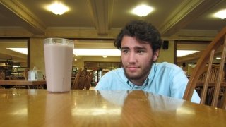Jake Saint Pierre, sitting in a dining hall, looks at a glass of chocolate milk.
