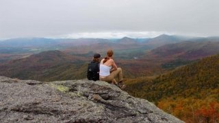 Two Saint Lawrence students sit on the summit of a mountain in the Adirondack Park. 