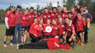 A group of Saint Lawrence ultimate frisbee players, wearing red jerseys, stand in a group. 