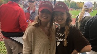 Abbie Cooper and Abby Eberle, wearing red Saint Lawrence hats, attend a football game. 