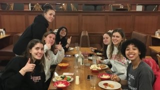 A group of Saint Lawrence students sit at a table and have a meal together. 