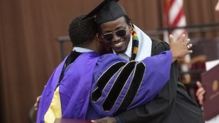 A graduate embraces a mentor at Commencement after receiving their diploma cover.