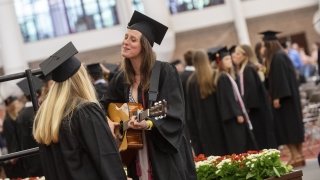Liv Hart ’20 stands and practices on her guitar with a classmate listening in.