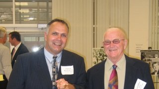 Two men stand holding hands.