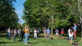Associate Professor David Murphy teaches an outdoor class underneath a large row of green trees.
