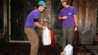 John and Kai, matching in stunning purple shirts, compete to see who can life the straight lake jug. If you look close enough, you can see the remains of woodworking on John’s pants.