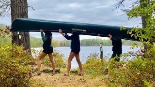Kai, Sage, and Lauren pose with the canoe in front of Town Line Pond.