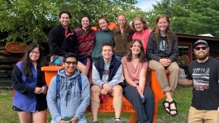 Arcadians smile in a giant Adirondack chair, thankful to be dry after a day of rafting.