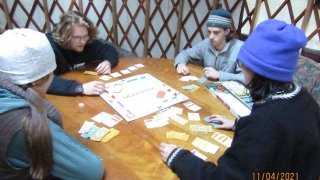 Arcadians huddle around the Community Yurt table playing Monopoly