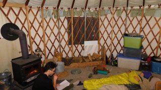 Kai Oakley completes his homework as Bri Duggan prepares to sleep in a warm yurt.