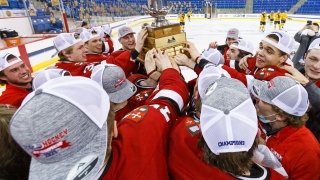 Men's Hockey team members crowd around a big gold-plated trophy after winning the ECAC Hockey title.