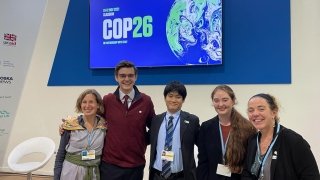 Elise Pierson and fellow delegates, wearing business professional attire and lanyards, attend the United Nations climate awareness conference.