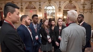 Several Saint Lawrence students, wearing professional attire, speak with an alumni during a networking event in Washington, D.C.