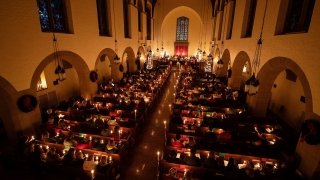 A balcony view of inside a full chapel during a candlelight service.