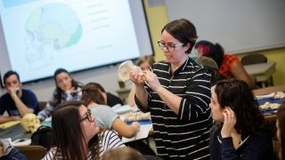 Minde Pitre, in a classroom of Saint Lawrence University students, examines skeletal remains.