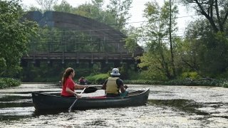 Two Saint Lawrence students navigate a river near campus in a canoe.