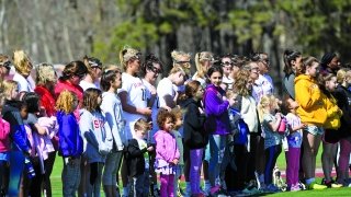 A photo of women's lacrosse players lined up with young community members. 