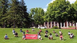 Students sitting on the grass with HEOP sign