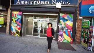 St Lawrence Trustee Elinor Tatum standing outside a colorful building in New York City that reads "Amsterdam News".