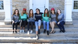 A photo of many St Lawrence students sitting on the stairs of Sykes Hall, each donning a Gretchen Scott clothing item.