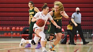 Women's basketball player dribbling around defender