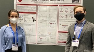 A student and faculty member stand in front of a chemistry research poster at a conference.