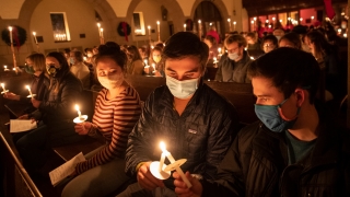 A photo of students sitting in the chapel lighting candles together. 