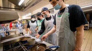 Four students stand over a hot stove, heating up chocolate.