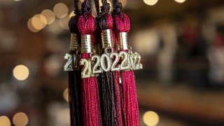 Scarlet and Brown graduation cap tassels with Class of twenty-twenty-two charms dangling from them.