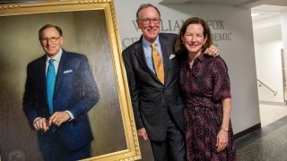 Saint Lawrence President Emeritus William Fox and Lynn Fox stand beside an oil portrait of William Fox.