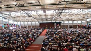 A wide view of Newell Field House full of seated Commencement attendees.