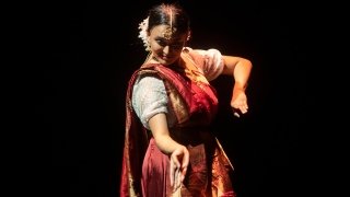 Anuva Anannya, wearing traditional clothing, performs on stage.