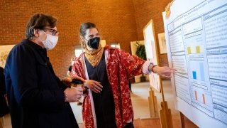 A student stands next to their research poster and discusses their project with Brian Morris.