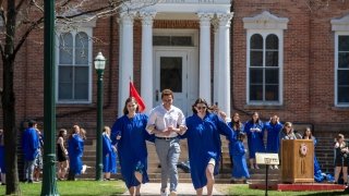 Three students run down the sidewalk during the Omicron Delta Kappa honor society ceremony.