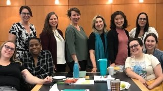 A group of Saint Lawrence faculty members stand near a long table while attending a professional development retreat.
