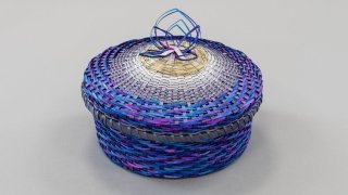 A vibrant royal blue and purple woven Indigenous basket.