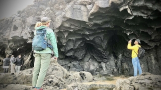 Two students stand beneath a cave-like rock structure, observing the rigid formations of their surroundings.