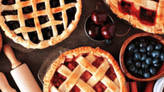 A table full of a variety of golden fruit pies. 