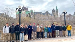 STUDENTS AND JOSEPH JOCKEL STANDING ALONG THE RIDEAU LOCKS, WITH PARLIAMENT IN THE BACKGROUND