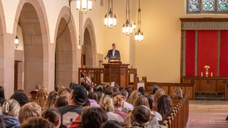 Jeff Frank stands at a podium in Gunnison Memorial Chapel and addresses a full crowd.