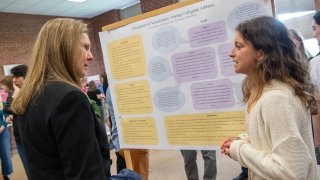 Saint Lawrence President Kathryn Morris speaks with a student about their research on perceptions of vulnerability among collegiate athletes during Festival Day.