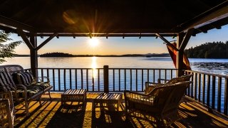The sun sets over Upper Saranac Lake. A scarlet and brown flag waves off a porch.