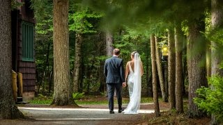 A bride and groom walk along a trail in the Adirondack mountains.