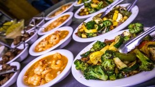 Several white plates feature fresh shrimp jambalaya, roasted squash, and broccoli.