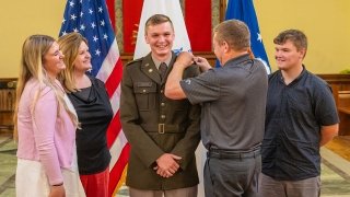 Photo of Saint Lawrence University Army Cadet getting his commisionary pin with his family at his side inside of Gunnison Chapel.