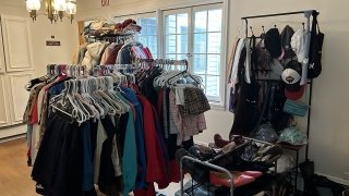 Clothing and accessories hanging on clothing racks, and shoes on a shoe rack, at the new thrift store location at 11 Hillside.