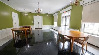 This common area in Gaines Hall has green walls, black-and-white tile flooring, and round wooden tables with chairs. Large windows and glass doors let in natural light, and chandeliers add a classic touch. The space is open and can be used for studying or small gatherings.