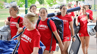 Student-athletes helping families haul luggage on move-in day