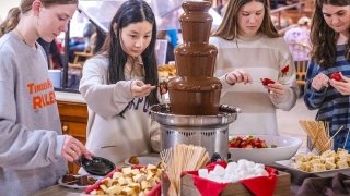 Students in Dana Dining Hall gather around a chocolate fountain, dipping strawberries, pound cake, and marshmallows.